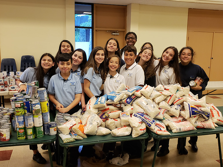 Our Lady of the Lakes School students pose with some of the donated meal items they would later pack into baskets for needy families at Thanksgiving.