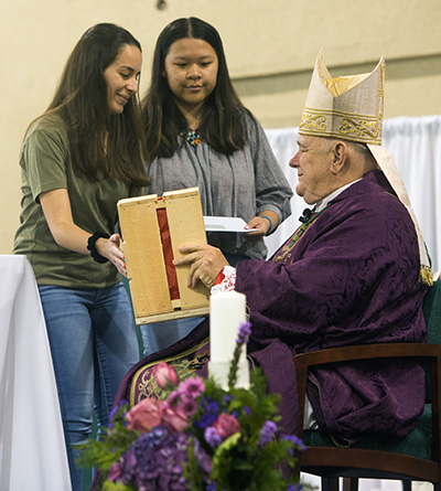 Immaculata-La Salle seniors Gianna Esposito, left, and Karlie Liang, president and vice-president respectively of the school's student government association, present a statue of Mary Help of Christians to Archbishop Thomas Wenski along with a monetary donation for charities in Haiti.