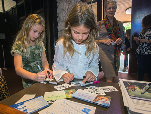 Charlotte Rosalski, 7, and Emilia Adams, 7, write their names on name tags before Mass Dec. 9 as part of St. Hugh's participation in the archdiocese-wide Welcome Weekend.