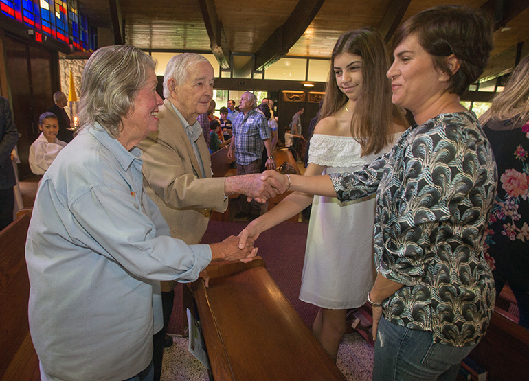 Kitty and Jim Harnett greet Anna Gatcliffe, 13, and Stacy Gatcliffe at the beginning of Mass Dec. 9 as part of St. Hugh's participation in Welcome Weekend in the Archdiocese of Miami.