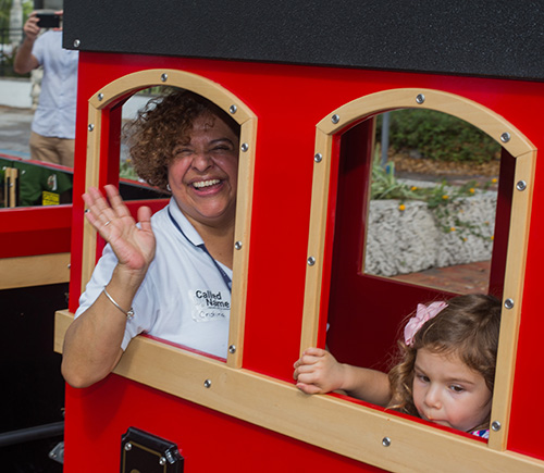 Cristina Fundora, St. Hugh Church's pastoral coordinator, waves from a window of the Mercy Train that offered rides around St. Hugh Church on Welcome Weekend.