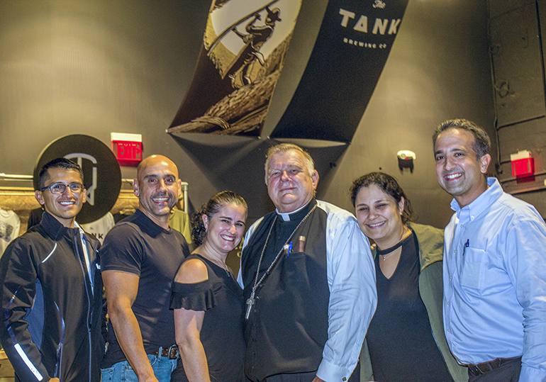 Archbishop Thomas Wenski poses with young adults at Theology on Tap Dec. 20, from left: Raul Velarde, Tony Carbot, Heidy Carbot, the archbishop, Angie Hernandez and Andy Hernandez.