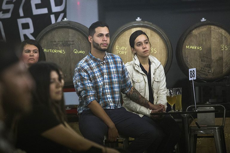 A couple of young adults listen to Archbishop Thomas Wenski during his talk at Theology on Tap, Dec. 20 at The Tank Brewery in Doral.