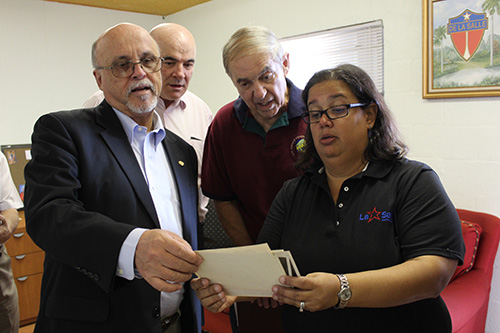 Monica Lauzurique, director of the La Salle Educational Center in Homestead, shows Brother Robert Schieler, far left, superior general of the De La Salle Christian Brothers, photos of the De La Salle schools in Cuba. Looking on are Brother Paulo Petry, center left, and De La Salle school from Cuba alumnus Hugo Castro. The superior general, some brothers and alumni visited the center in November 2018.