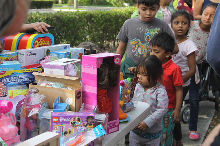 Children who accompany their parents to immigration appointments stand in line to receive toys for the feast of Three Kings. The toy distribution was organized by a group that calls itself the Círculo de Protección (Circle of Protection), which is made up of a number of community and social advocacy organizations. The volunteers meet every Wednesday in front of the ICE office in Miramar to hand out water, coffee and pastries to those waiting for their appointments.