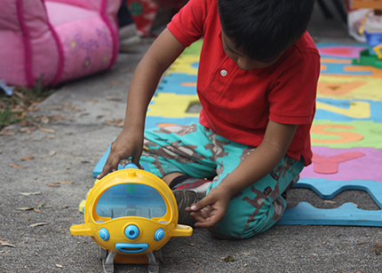 A boy plays with the toy he received while waiting with his parents outside the ICE office in Miramar.