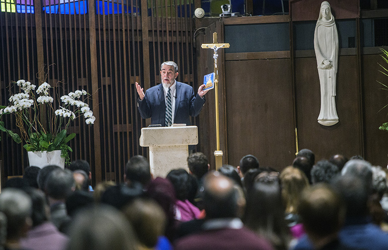 Scott Hahn holds a copy of his book, "Home Sweet Rome" as he shares his conversion story with an audience at St. Hugh Church in Coconut Grove.