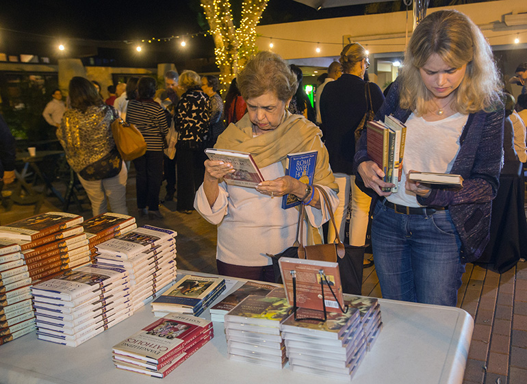 Saidy Barinaga and her daughter, Saidy Barinaga-Burch, look through Scott Hahn's books on the St. Hugh patio after his presentation.