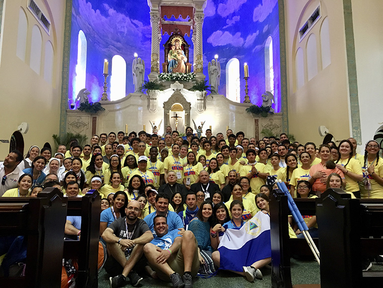 Los 135 peregrinos de la Jornada Mundial de la Juventud de Miami posan para una foto en el Santuario Nacional Corazón de María después de celebrar la Misa con los Obispos de La Florida y antes de embarcarse en el viaje de 10 millas al lugar de la vigilia nocturna y la Misa final del domingo con el Papa Francisco.