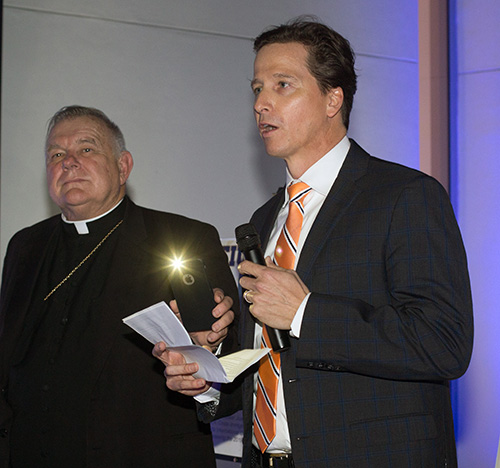 Archbishop Thomas Wenski holds up his cell phone flashlight so that St. Thomas University law professor and Immigration Clinic Director Michael Vastine can read his speech accepting the Mother Cabrini award for pro bono service.