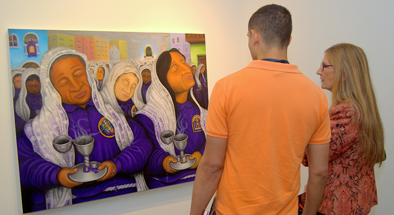 Two art enthusiasts admire Hugo Orezzoli’s canvas Incense Bearers during the opening of his show at St. Thomas University.