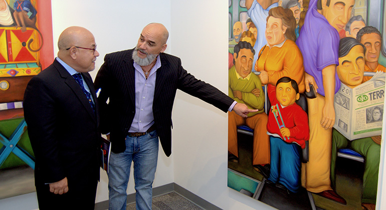 Hugo Orezzoli, a la derecha, muestra su pintura "El autobús" a David Hurtado Fudinaga, cónsul general adjunto del Perú en Miami, durante la inauguración de la muestra de arte de Orezzoli, en la Universidad St. Thomas.