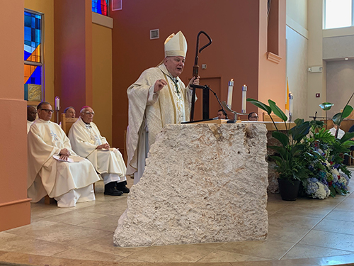 Archbishop Thomas Wenski preaches the homily during the Mass marking the 15th anniversary of the dedication of St. Anthony Chapel on the campus of St. Thomas University in Miami Gardens. Behind him, far left, is Msgr. Franklyn Casale, past president of St. Thomas U. At right is Bishop Luis del Castillo, emeritus of Melo, Uruguay.