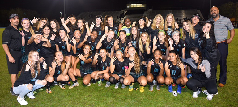 Archbishop McCarthy High School's Lady Mavericks celebrate with their coach, Mike Sica, far left, and principal, Richard P. Jean, far right, after beating St. Thomas Aquinas' Raiders 1-0 in the regional semifinal Feb. 8. The Lady Mavericks went on to beat West Boca Raton, 4-0, in the regional final Feb. 12, and St. Petersburg, 4-1, in the state semifinal Feb. 15, to reach the state championship game, set for Feb. 22.