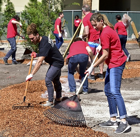 Workers spread mulch for a walking path at Camillus House in Miami. Wearing red shirts are workers from the Dow Chemical Company, with black shirts on Camillus House staffers.