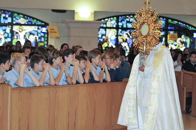 Father Elvis Gonzalez, director of vocations for the Archdiocese of Miami, processes with the Blessed Sacrament at the conclusion of the Focus 11 vocations rally Feb. 27 at host St. Gregory Parish in Plantation.