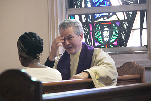 Father Lazarus Govin, pastor of St. Martha Parish in Miami Shores, pretends to start a confession with Tamara Genna during the taping of a Reconciliation Weekend promotional video at St. Mary Cathedral.