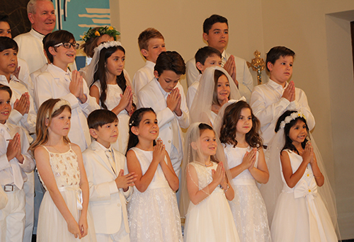 Father Michael Grady, pastor of St. Anthony Parish, gathers with children after they received their first Communion May 2 at the Fort Lauderdale church.