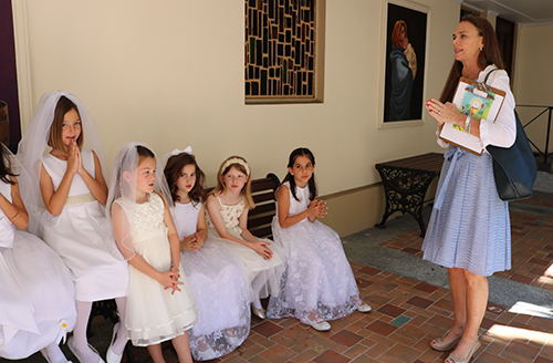 St. Anthony catechist Dot Bevins talks to young girls moments before the start of the Mass where they received their first Communion.