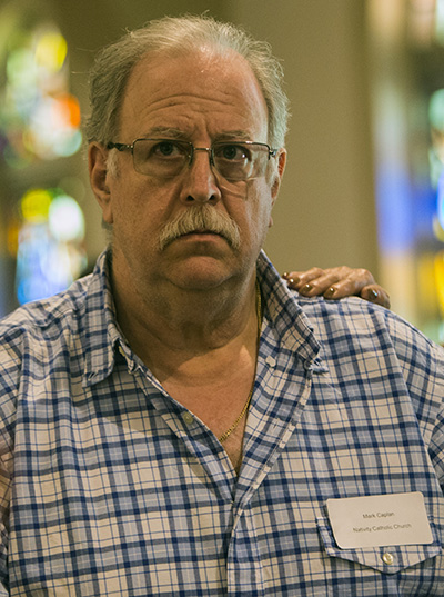 Mark Caplan, 60, a catechumen from Nativity Church in Hollywood, stands as his sponsor places her hand on his shoulder and affirms his commitment to join the Catholic faith.