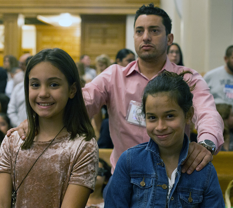 Mauro Domine sponsors his daughter, Keira Domine, 11, and her friend, Laura Ronquillo, 11, during the Rite of Election ceremony March 10 at St. Mary Cathedral. Archbishop Thomas Wenski admitted 494 catechumens as members of the elect as they prepare to receive the sacraments of initiation into the Catholic Church at the Easter Vigil. The Rite of Election ceremony took place the Sunday after Ash Wednesday, March 10, at St. Mary Cathedral in Miami.