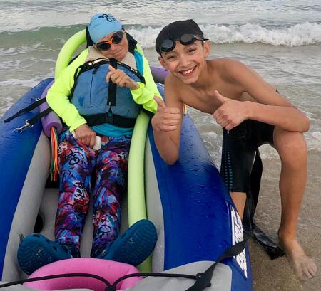 Lewis Perez, a sixth-grader at St. Mark School, gives a thumbs-up at the April 14 South Beach Triathlon. He teamed up for the event with disabled athlete Kerry Gruson, left, of ThumbsUp International.