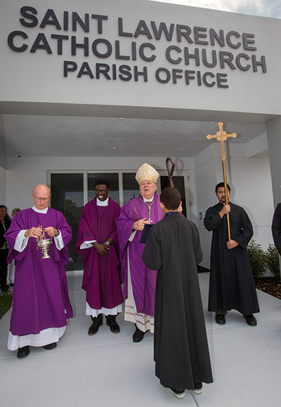Archbishop Thomas Wenski conducts the blessing ceremony in front of St. Lawrence Church's new parish office building. Father Cletus Omode, the parish administrator, stands next to him.