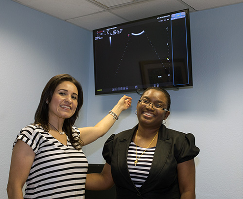 Ultrasound technician Lorena Villaneda-Romero, left, points to a big-screen television that displays a picture of the unborn baby that the mother can see, as she stands next to Judnis Francois, coordinator of the Central Broward Pregnancy Help Center.