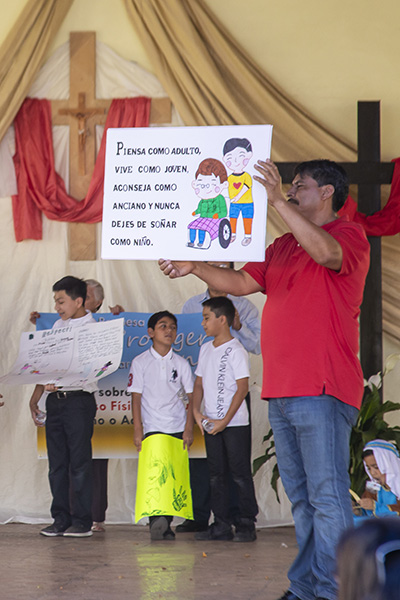 Manuel Gallegos, director of the Hispanic Pastoral Council at St. Clement Church, holds a sign to create awareness of the need to protect the elderly during the parish's Safe Environment Awareness and Prevention Family Day.