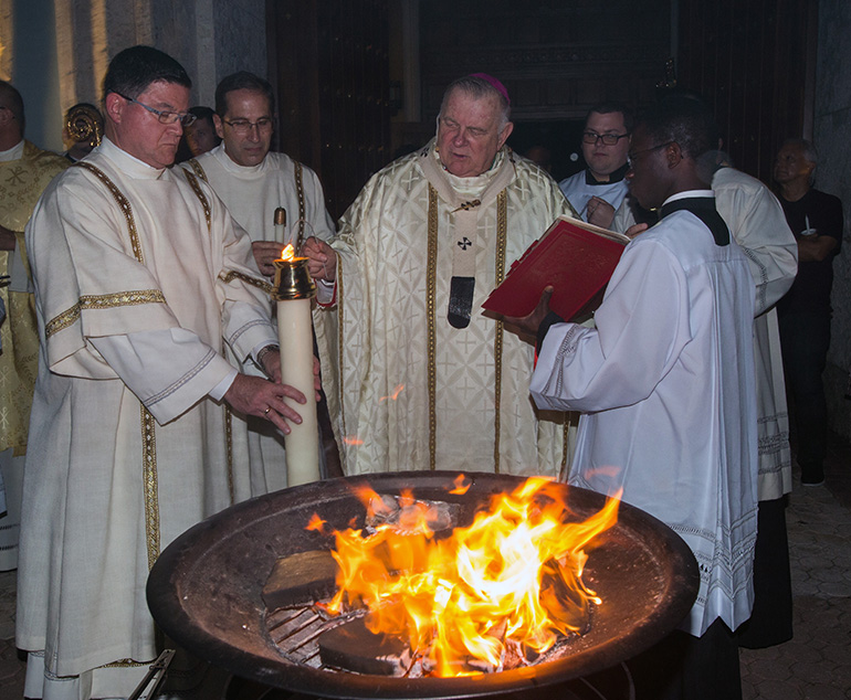 Archbishop Thomas Wenski lights the Paschal Candle at the start of the Easter Vigil Mass at St. Mary Cathedral, April 20, 2019. The new fire of the candle symbolizes life in Christ, with the candle representing the risen Lord.