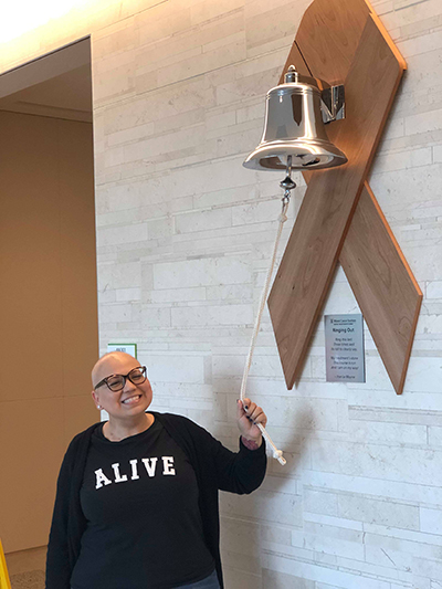 Angela Suazo rings the treatment completion victory bell at the Miami Cancer Institute of Baptist Health South Florida. The plaque beneath has a poem by Irve Le Moyne which states: Ring this bell three times well its toll to clearly say, my treatment's done, this course is run and I am on my way!