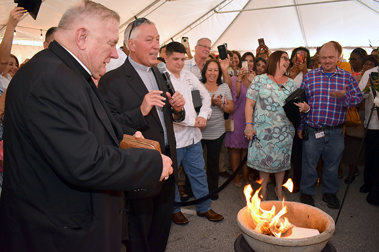 Archbishop Thomas Wenski, left, and Father John Peloso watch the burning paid-off mortgage of St. Edward Church.