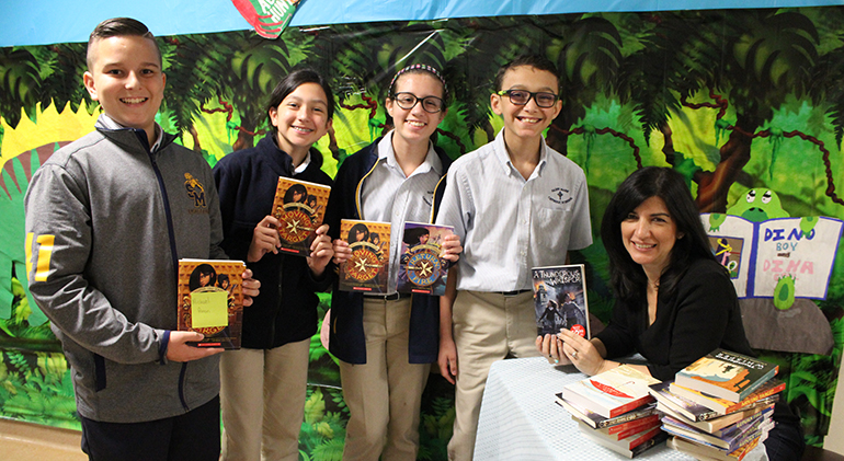 Los estudiantes de la escuela St. Mark, Michael Anon, Alba Millon, Ayva Dow y Lewis Pérez posan con sus libros junto a la autora del mismo, Christina Díaz González.