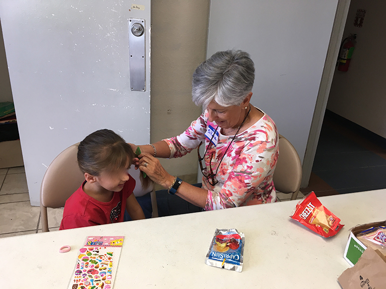 Silvia Muñoz, director of social action for the Jesuits’ Pedro Arrupe Institute in Miami, combs the hair of a child who arrived at the Casa Oscar Romero shelter in El Paso, Texas, with her father. Muñoz spent two weeks in March volunteering at the shelter.