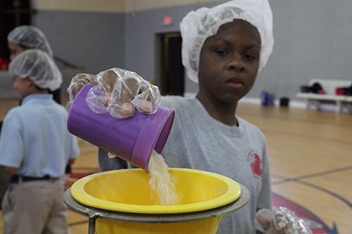 St. Rose of Lima School fourth grader Zakary Phanord pours rice into a funnel during a Meals of Hope packing event in the school gym April 30. During Lent, fourth graders from the school raised more than $ 1,500 to buy and package 6,000 meals, all of which were donated to St. Martha Church, Miami Shores, food pantry.