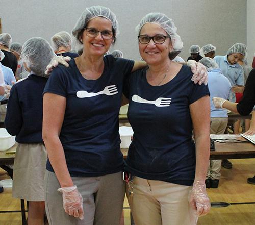 Forks fighting hunger (Tenedores contra el hambre): las maestras de la escuela St. Rose of Lima, Paulina Cuadrado, izquierda, y Claudia Karleskey posan para la foto en el evento de empaque de comidas, Meals of Hope, en su escuela, el 30 de abril.