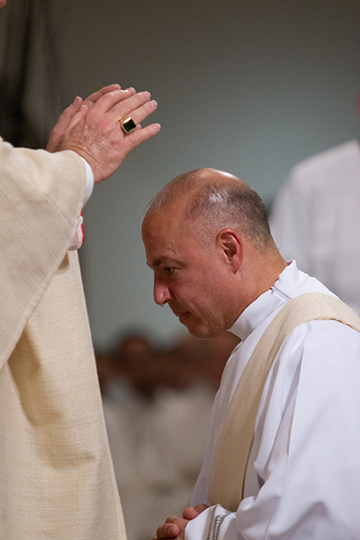 El Arzobispo Thomas Wenski impone sus manos sobre el muy emocionado  Diácono Elkin Sierra, ordenándolo sacerdote para la Arquidiócesis de Miami.