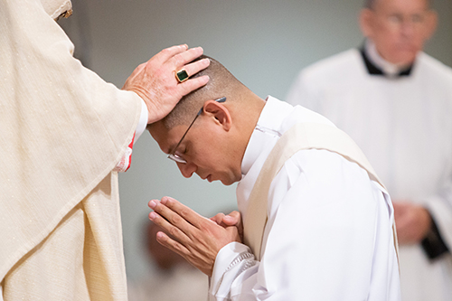 Archbishop Thomas Wenski lays hands on Deacon Yonhatan Londoño, ordaining him a priest for the Archdiocese of Miami.