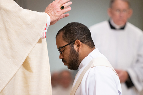 El Arzobispo Thomas Wenski impone sus manos sobre el Diácono José Enrique López, ordenándolo sacerdote para la Arquidiócesis de Miami.