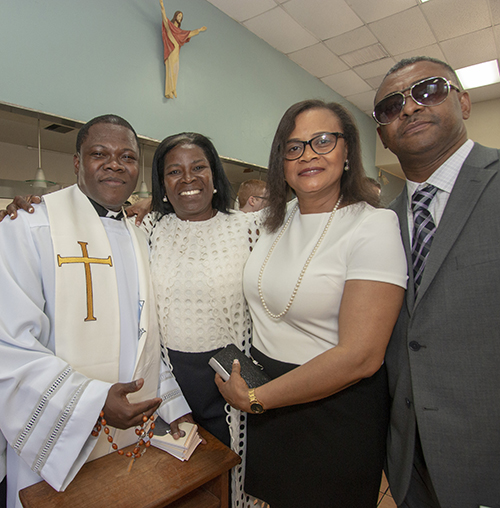 While giving out blessings, newly ordained Father Reynold Brevil poses with Ketty Descardes, second from right, the woman "who started it all" - his priesthood in the Archdiocese of Miami. Also pictured, her husband, Francois, and another friend, Morosi Lila Louis.