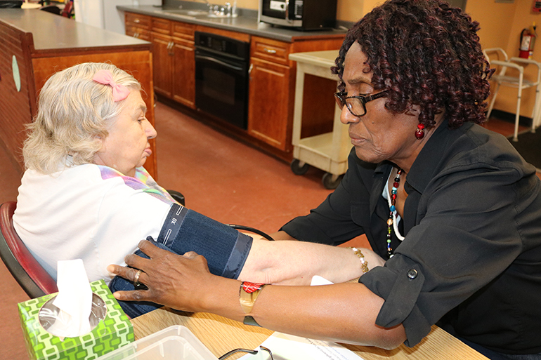 Evelyn Pierre-Louis, a certified nursing assistant, takes Theresa Zarzycki's blood pressure, a routine practice at Catholic Charities adult daycare centers making sure their clients are healthy and in top condition. Zarzycki is a client of Central West Adult Day Care Center in Davie.