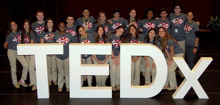 Students group behind the logo of TEDx, a forum of speeches and performances they helped to produce at St. Thomas Aquinas High School in Fort Lauderdale.