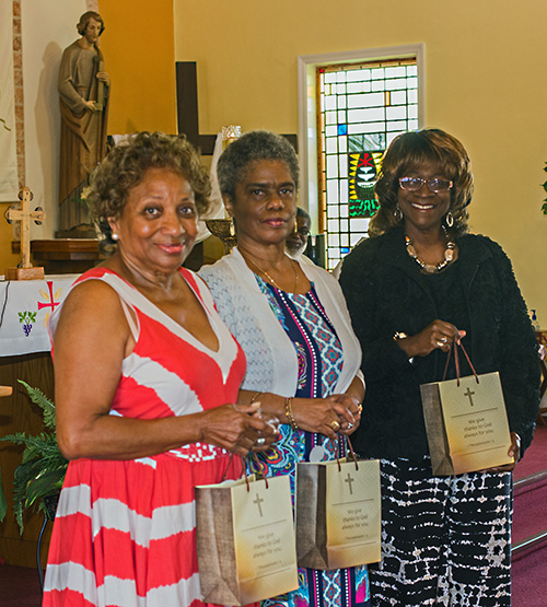 From left, Teresa Davis, Andrea Patterson and Constance Thornton hold the gifts given to them for their service to St. Philp Neri Church on the day the parish celebrated its 65th anniversary, May 26, 2019.