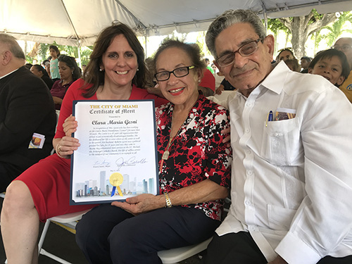 Madelyn R. Llanes, left, program director of Centro Mater East I and II, poses with veteran teacher Clara Gesni and her husband, Roberto, and the Certificate of Merit she received from the City of Miami upon her upcoming retirement.