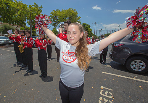 Cheerleader Rebecca Pryor, a junior, performs as band members play Cardinal Gibbons High School's fight song at the blessing and groundbreaking ceremony for the school's new STEAM center.