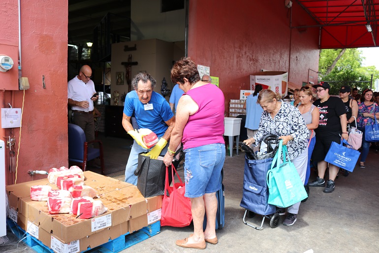 Cientos de surfloridanos reciben comida gratis de la Sociedad de San Vicente de Paul, el 8 de junio, en el nuevo local del banco de comida de la parroquia Mother of Christ, en Kendall, al sur del aeropuerto Tamiami.