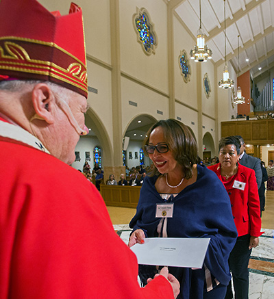 Luz Consuelo Chiessa, graduada de la Escuela de Ministerio, recibe su Certificado de Estudios Católicos del Arzobispo Thomas Wenski, durante la Misa del 8 de junio de 2019.