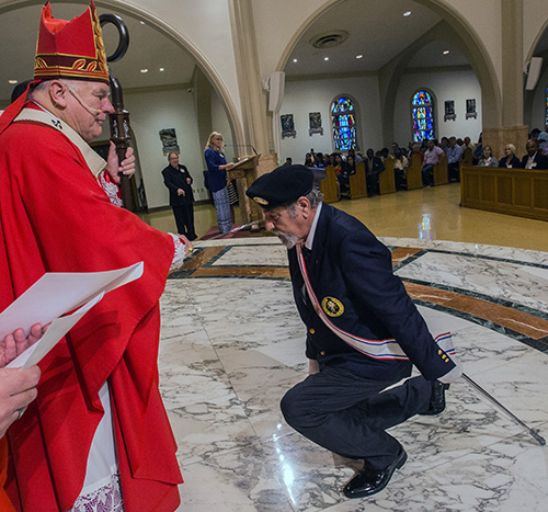 El Arzobispo Thomas Wenski blande una espada para bendecir al Caballero de Colón Salvatore Carnazza, de la iglesia St. Bonaventure, en Davie, al volver a comisionarlo para servir a los enfermos y a los inválidos.