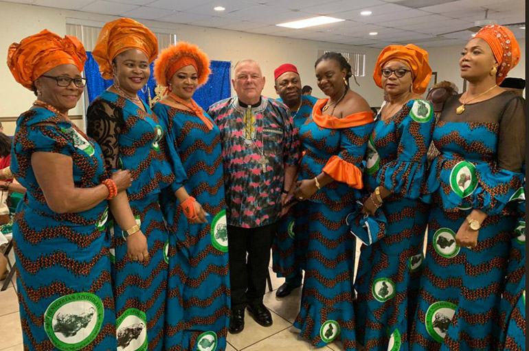 Wearing traditional garb, Archbishop Thomas Wenski poses with some of the members of the Nigerian Apostolate here after the Mass to mark its 25th anniversary in the archdiocese, June 16, 2019.