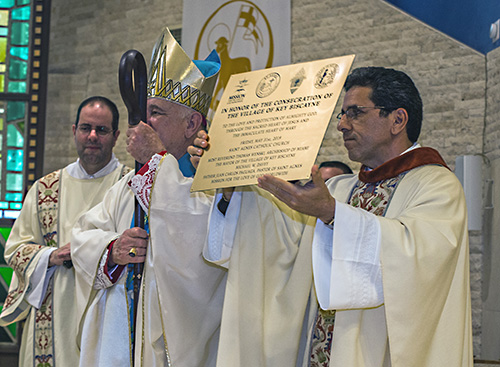 Father Juan Carlos Paguaga, pastor of St. Agnes Church, holds up the plaque commemorating the May 31 consecration of Key Biscayne to the Sacred Hearts of Jesus and Mary. Archbishop Thomas Wenski consecrated the Village of Key Biscayne to the Sacred Hearts of Jesus and Mary May 31, feast of the Visitation.